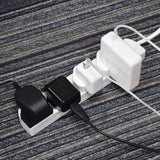AVSL Mercury 4 gang extension lead in white ABS with three UK chargers plugged in, resting on a grey striped carpet.