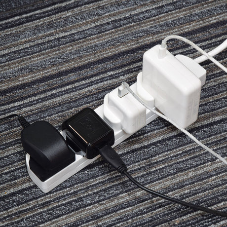 AVSL Mercury 4 gang extension lead in white ABS with three UK chargers plugged in, resting on a grey striped carpet.