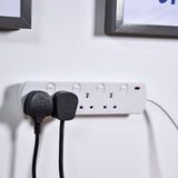 AVSL Mercury 4 gang switched extension lead in white mounted on a wall with two black UK plugs connected, below dark picture frames.