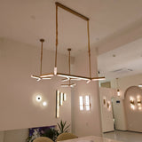 Elvaris LED Small Vertical Alabaster Wall Light in Brushed Brass, shown illuminated among pendant and wall lighting in a modern showroom setting.