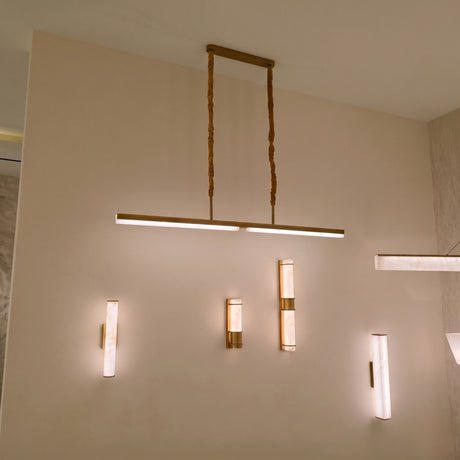 Elvaris LED Linear Alabaster Chandelier in brushed brass, shown suspended from a ceiling plate on twisted cords above a wall with matching alabaster wall lights.