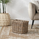 Tobs Grey Kubu Rattan Magazine Basket, 30cm tall, rectangular woven storage basket shown on a rug beside a sofa and potted plant in a living room setting.