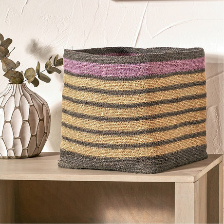 Square seagrass storage basket, 30cm, with natural woven body, grey stripes and a lilac band near the rim, shown on a wooden console beside a vase.