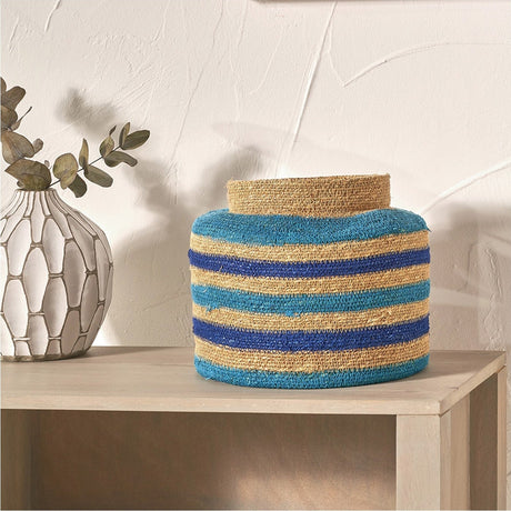 Seagrass storage basket, 26cm, with natural, blue and turquoise striped weave, shown on a console table beside a vase with eucalyptus stems.
