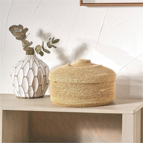 Seagrass Natural Lidded Basket Tub, 30cm, round woven storage basket with domed lid, shown on a wooden shelf beside a patterned vase and dried leaves.