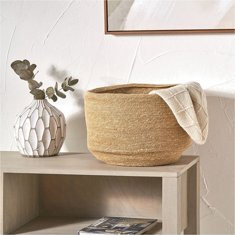 Seagrass Natural Basket Tub, 34cm, woven wicker storage basket with cream throw draped over the side, styled on a wooden bench beside a vase.