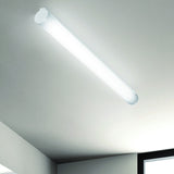 Bath A LED Linear Flush Ceiling Light in white, a single tube of opal polycarbonate with round end caps, shown illuminated on a white ceiling corner.