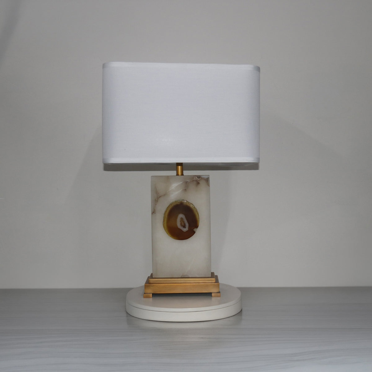 Selune table lamp with rectangular alabaster base, agate slice inset, brushed brass stem and plinth, and white fabric shade.