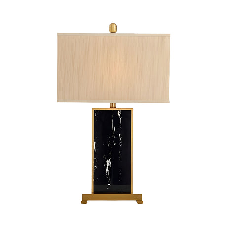 The Valmor 1 Light Block Marble Table Lamp features a modern black marble rectangular base, brass accents, and a large rectangular beige fabric shade, shown against a white background.
