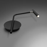 MiniSpot LED wall light in black iron with round wall plate, angled rod arm, and cylindrical spot head with grey collar joint, shown lit on a grey background.
