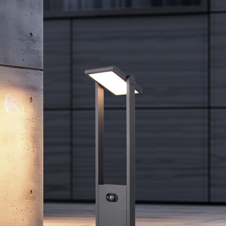 Malawi Solar LED White PIR Lamp Post in anthracite, a tall outdoor post light with an angled rectangular head and integrated PIR sensor, shown illuminated against a dark textured wall.