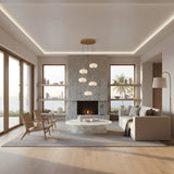 A modern living room with large windows, a stone fireplace, round marble coffee table, beige sofa, and minimal decor features the Aurevia 5 Light LED Dome Alabaster Cluster Pendant Light – Brushed Brass, overlooking an ocean view with palm trees.