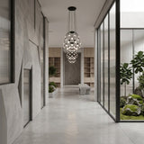 A modern hallway with gray concrete floors, geometric walls, and glass accents features the Mesh LED Small Suspension Light - Black. Pendant lighting, indoor plants, and abundant natural light complete the minimalist, inviting space.