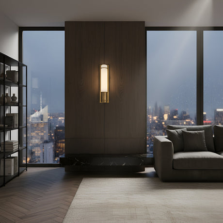 A modern living room with large windows showcasing a city skyline at dusk, a gray sofa, black shelving unit, Averna LED Small Framed Alabaster Wall Light in Soft White & Brushed Brass, wooden flooring, and a neutral area rug.