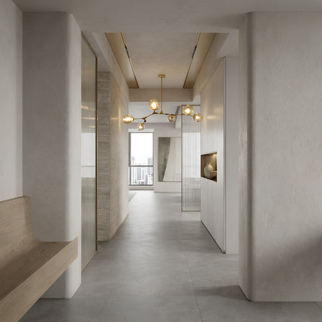 Niori Tree 6 Light Suspension in Gold with branching arms and glass globes, hanging in a minimalist hallway with wood bench, white walls, and city view.