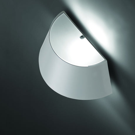 Fennorne Wall Light in White & Silver, a curved iron half-shade fixture mounted on a dark grey wall, casting an upward and downward glow from its silver-lined interior.