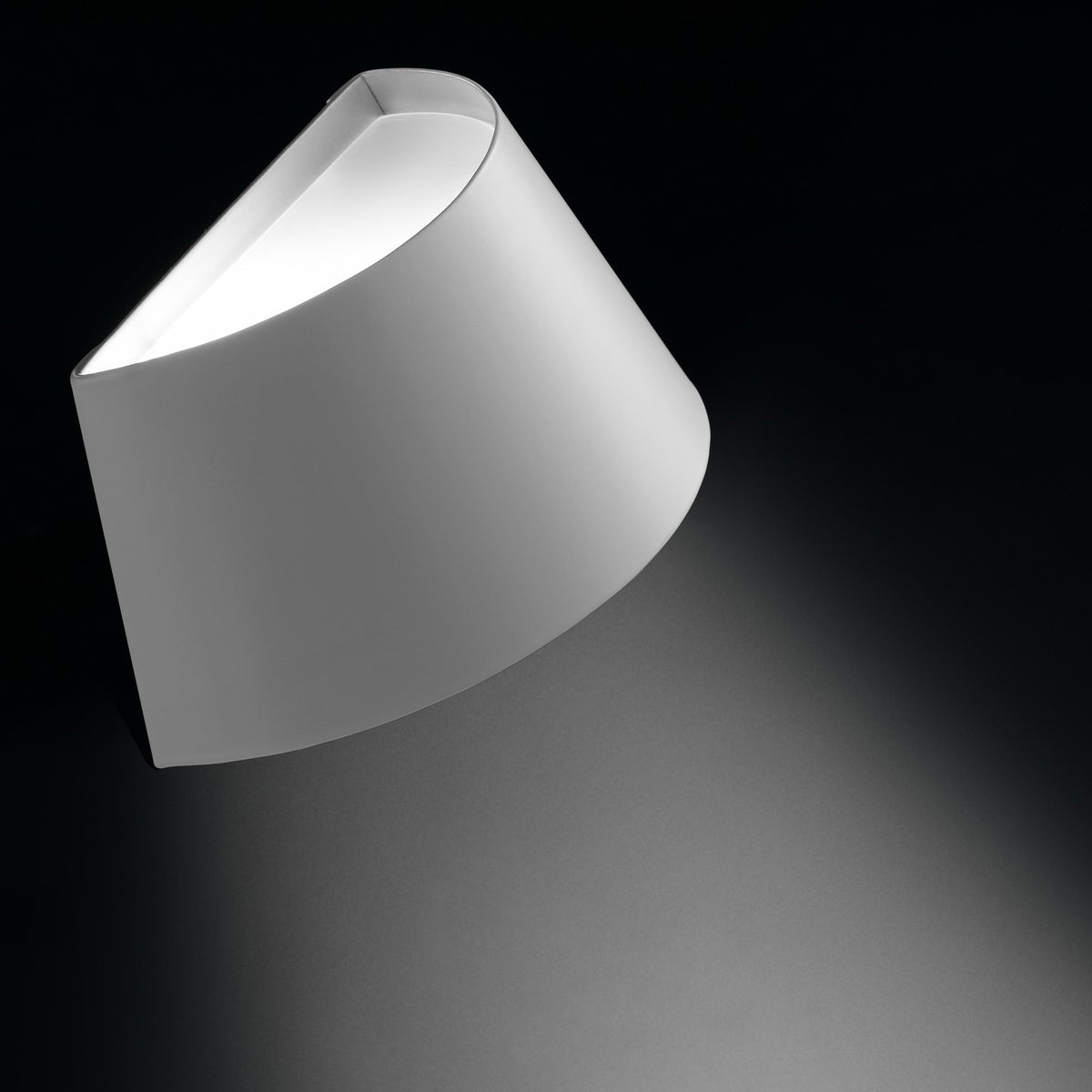 Fennorne Wall Light in white with a silver interior, a single curved iron shade angled on a dark background, casting soft light upward and downward.