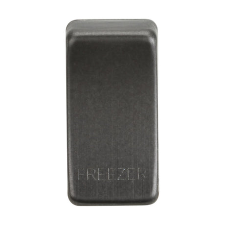 A close-up of the smoked bronze rectangular object labeled "FREEZER" is captured, showcasing its sleek and modern matte finish. This piece, resembling interchangeable switch covers, suggests versatility and is set against a plain white background for a contemporary look.