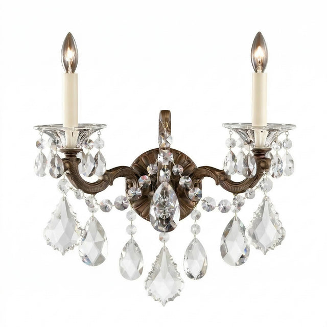 The Vienna 2 Light K9 Crystal Wall Light features two candle-style bulbs, ornate bronze arms, and hanging K9 crystal pendants for a luxurious Rococo accent that adds elegance and sparkling light to any space.