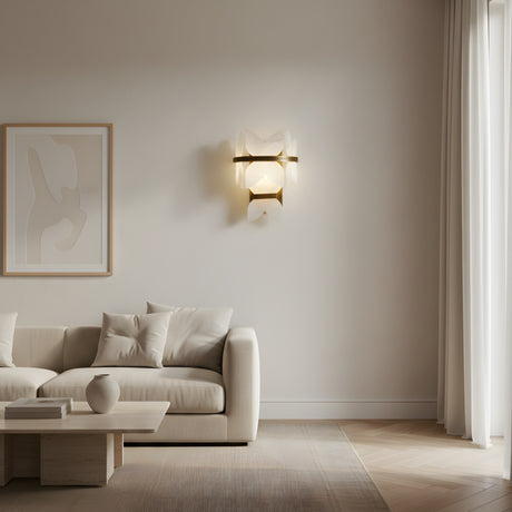 A minimalist living room with a cream sofa, matching cushions, a low wooden coffee table with a vase, abstract wall art, the Petraia LED Floral Alabaster Wall Light in brushed brass and soft white, and sheer curtains letting in natural light.