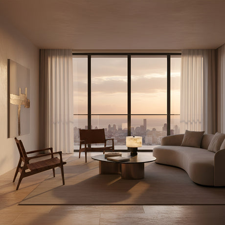 A modern, minimalist living room features a curved sofa, wooden chairs, round coffee table, and a city skyline view at sunset. The Stravion 1 Light Large Ribbed Marble & Alabaster Table Lamp in soft white & black adds calm with sheer neutral curtains.