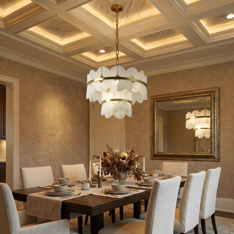 Elegant dining room with a dark wood table, eight white upholstered chairs, a floral centerpiece, gold-framed mirror, and the Petraia LED 2 Tier Floral Alabaster Chandelier in brushed brass & soft white beneath a coffered, lit ceiling.