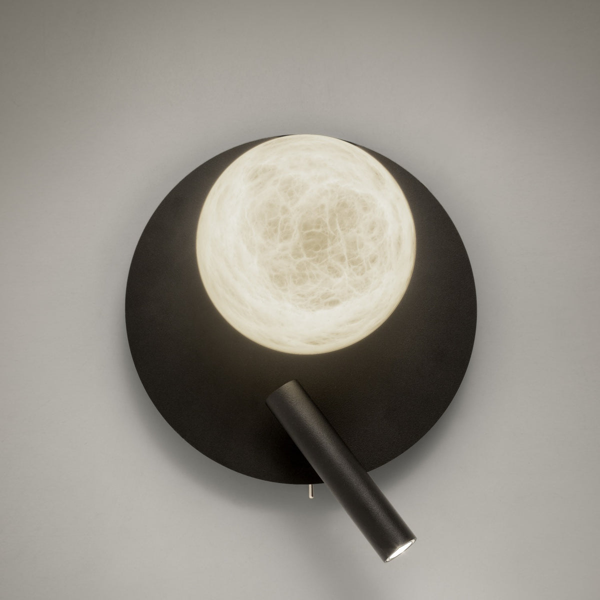 Halvessa LED Alabaster Wall Light in black, with a round textured iron plate, glowing alabaster globe, and angled reading light arm on a plain grey background.