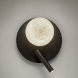 Halvessa LED Alabaster Wall Light in black, with a round textured iron plate, glowing alabaster globe, and angled reading light arm on a plain grey background.
