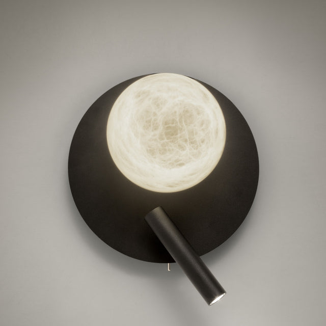 Halvessa LED Alabaster Wall Light in black, with a round textured iron plate, glowing alabaster globe, and angled reading light arm on a plain grey background.