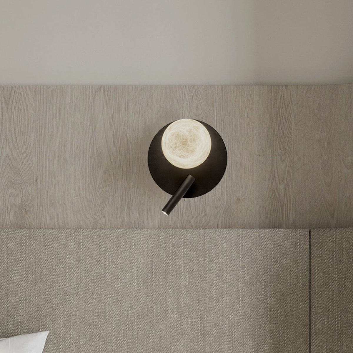 Halvessa LED Alabaster Wall Light with Reading Light in black, round iron plate with glowing alabaster globe and slim angled reading arm, shown above a bed.