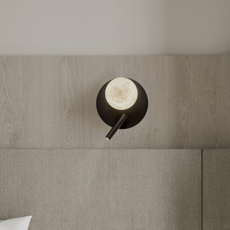 Halvessa LED Alabaster Wall Light with Reading Light in black, round iron plate with glowing alabaster globe and slim angled reading arm, shown above a bed.