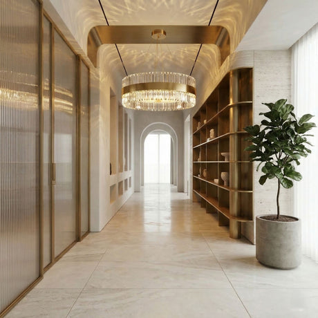 A modern hallway with marble floors, a large potted plant, gold shelving, the Liberty LED Crystal Glass Chandelier - Gold, glass doors on one side, and tall windows with sheer curtains on the other.