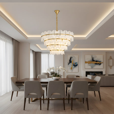 A modern dining room with a dark wood table, eight light upholstered chairs, abstract art, floor-to-ceiling windows with sheer curtains, white orchids on the table, and a Petraia LED 4 Tier Floral Alabaster Chandelier in brushed brass & soft white.