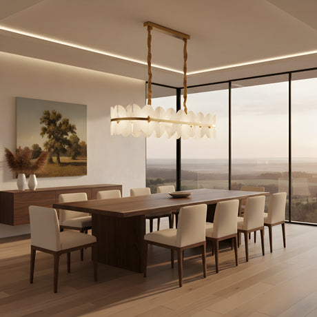 A modern dining room with a large wooden table, eight white chairs, Petraia LED Linear Floral Alabaster Chandelier in brushed brass & soft white, floor-to-ceiling windows framing a scenic view, plus a sideboard with vases and artwork.