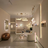 Aureon LED Triple Ring Alabaster Chandelier in brushed brass, three staggered alabaster rings suspended above a living room seating area with warm ambient lighting.