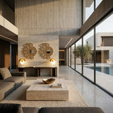Modern living room with large windows, neutral tones, a gray sectional sofa, stone coffee table, and two decorative mirrors. The Lucia LED Table Lamp in white adds warmth to the airy space with views of a pool and olive tree outside.