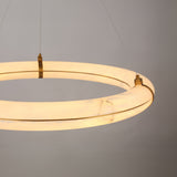 Aureon LED Alabaster Ring Chandelier 800mm, close-up of glowing stone ring in brushed brass cradle mounts with cable suspension, plain grey background.