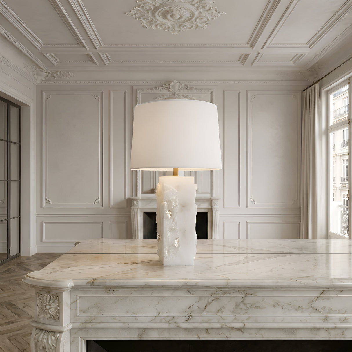 The Kavryn 1 Light Raw Cut Alabaster Table Lamp in brass and soft white with a rectangular shade sits on an ornate marble desk in an elegant room featuring paneled walls, intricate ceilings, large windows, and a fireplace.