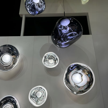 The Lava Medium LED Pendant Light - Smoked features a rounded, glassy design with a metallic finish, mounted on a white ceiling to create modern reflections and abstract patterns in this overhead view.