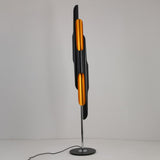 The Stealth 6 Light Floor Lamp in brass and black features cylindrical elements on a slim chrome stand with a round base, presented against a plain white background.