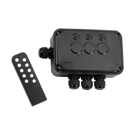 An IP66 13A 3 Gang Remote Controlled Switch Box, featuring a black remote control with multiple buttons, is positioned next to the rectangular black electrical junction box. It boasts circular features and three cable entry points. This weatherproof design ensures reliable performance and durability in challenging conditions.