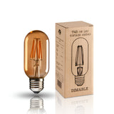 Schuller Vintage T45 LED bulb with amber glass, visible inner filaments and E27 base, shown beside its kraft product box on a white background.