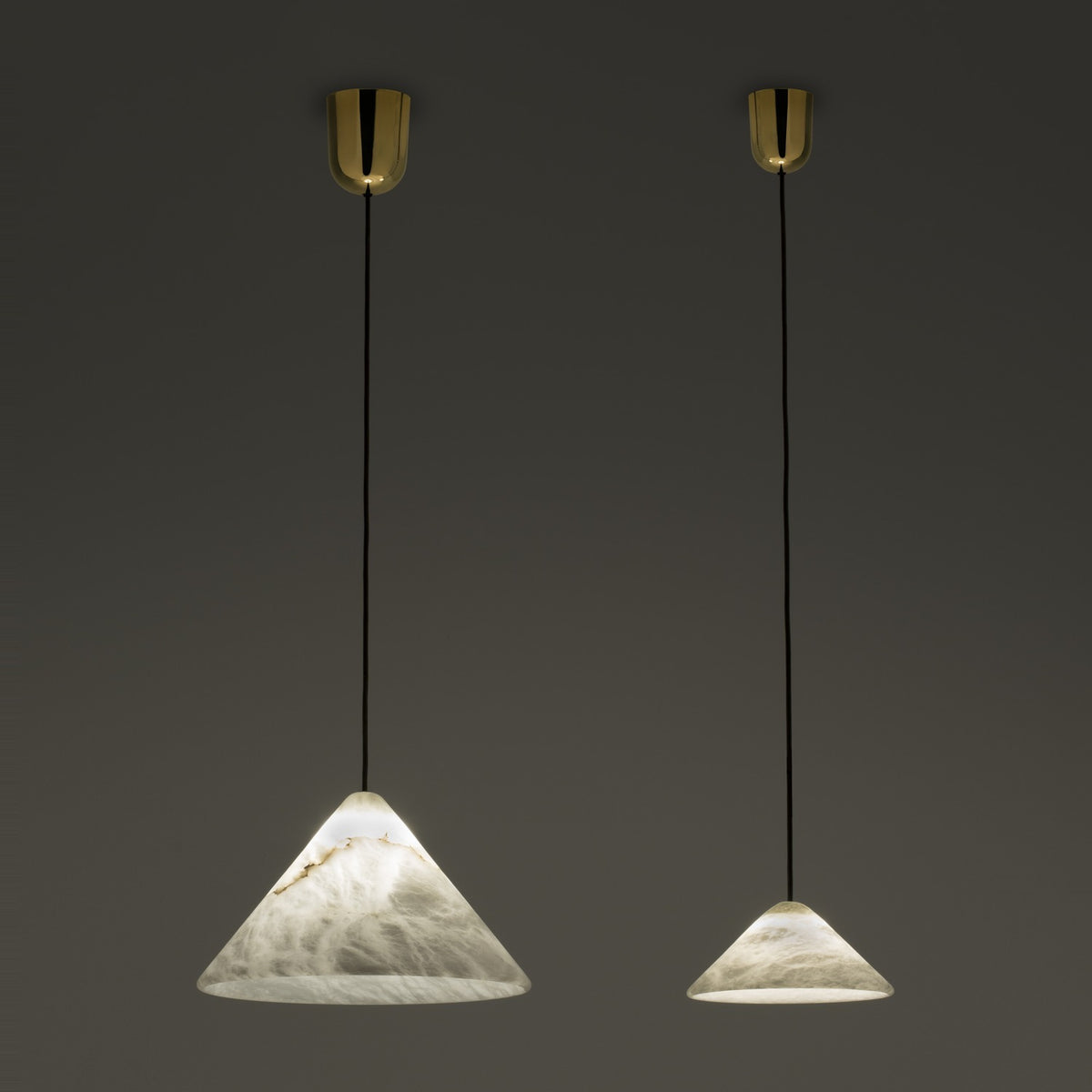 Fuji LED Alabaster Pendant Light in two cone sizes with polished brass ceiling canopies and black cords, shown illuminated against a dark background.