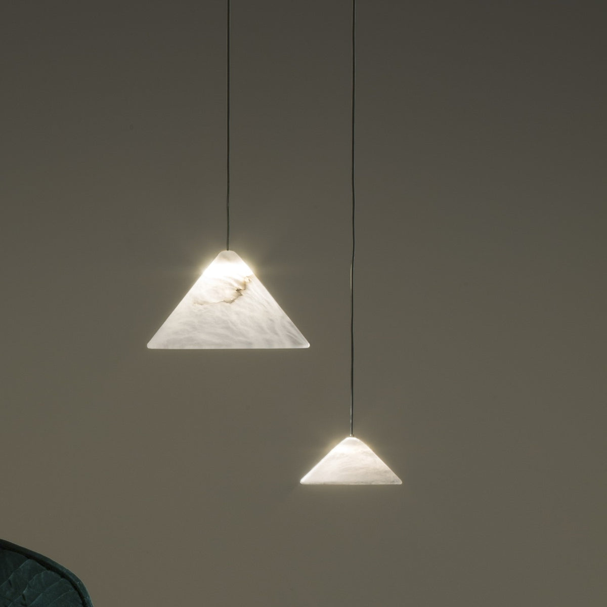 Fuji LED Alabaster Pendant Light in two sizes, cone-shaped white stone shades on slim black cords, glowing warmly against a muted grey background.