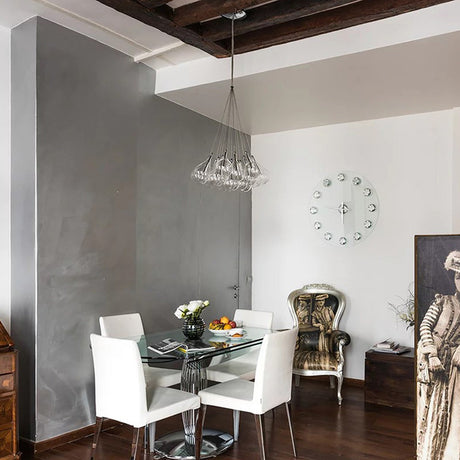 Yarvelle 19 Light Glass Pendant Light in chrome, clustered clear glass teardrop shades on thin wires, shown above a glass dining table in a modern grey and white dining room.