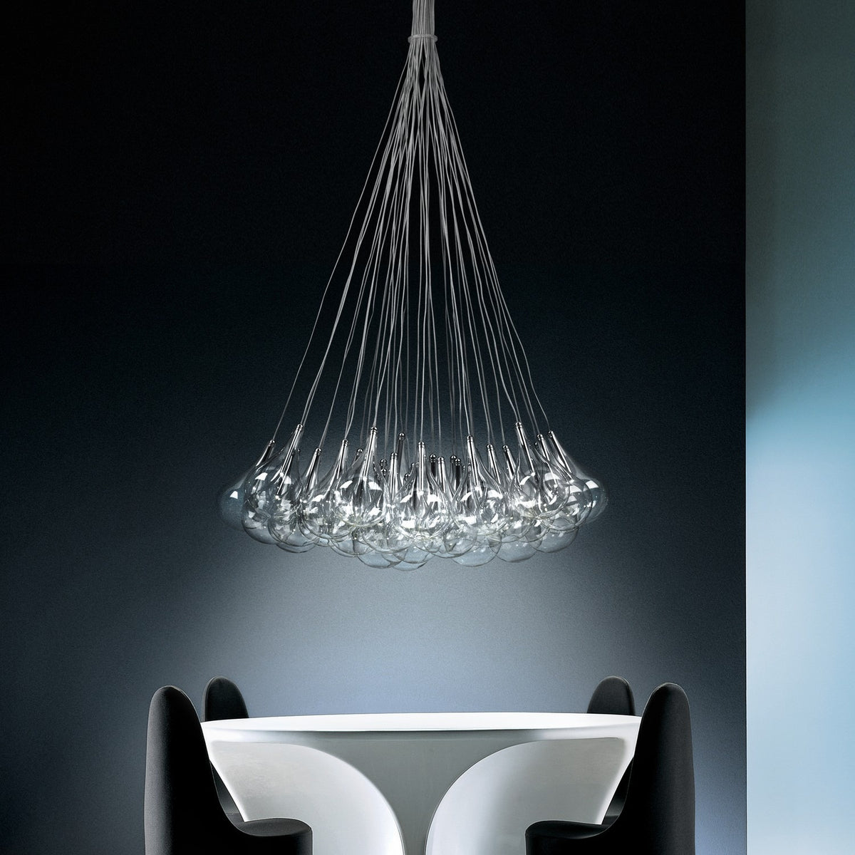 Yarvelle 37 Light Glass Pendant Light in chrome, clustered teardrop glass globes on fine cables converging to a single ceiling point, shown above a dining table in a dark-toned room.