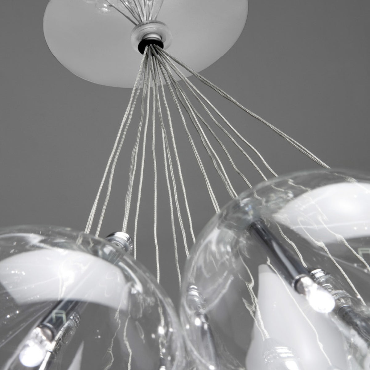 Close-up of the Yarvelle glass pendant light showing clear teardrop globes with chrome holders suspended on multiple cables from a white ceiling rose.