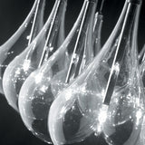 Yarvelle 24 Light Glass Pendant Light in chrome, close-up of clear teardrop glass shades with slim chrome stems and illuminated G4 lamps, set against a dark background.