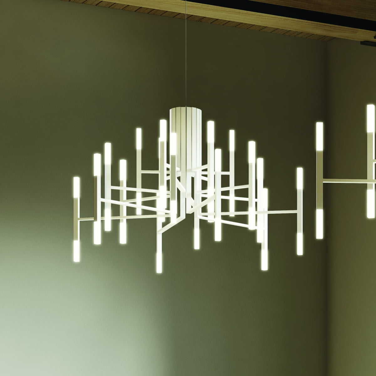 TheLight LED 18 Light Chandelier in white, with slim arms radiating from a fluted central cylinder, each carrying glowing vertical LED rods, shown against an olive-toned ceiling.