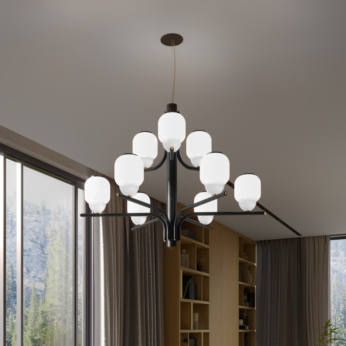 Faronne 9 Light Glass Chandelier in black, with tiered opal glass barrel shades on sweeping iron arms, shown suspended in a room with large windows and wood shelving.